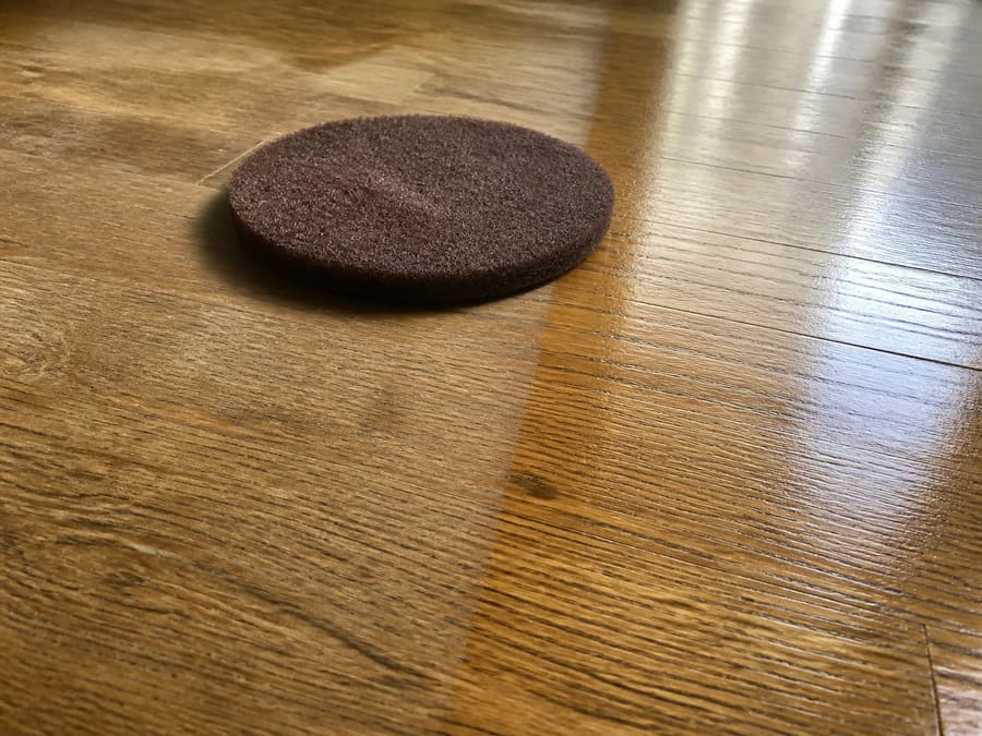 A floor buffer abrading the surface of a wood floor without cutting into the bare wood
